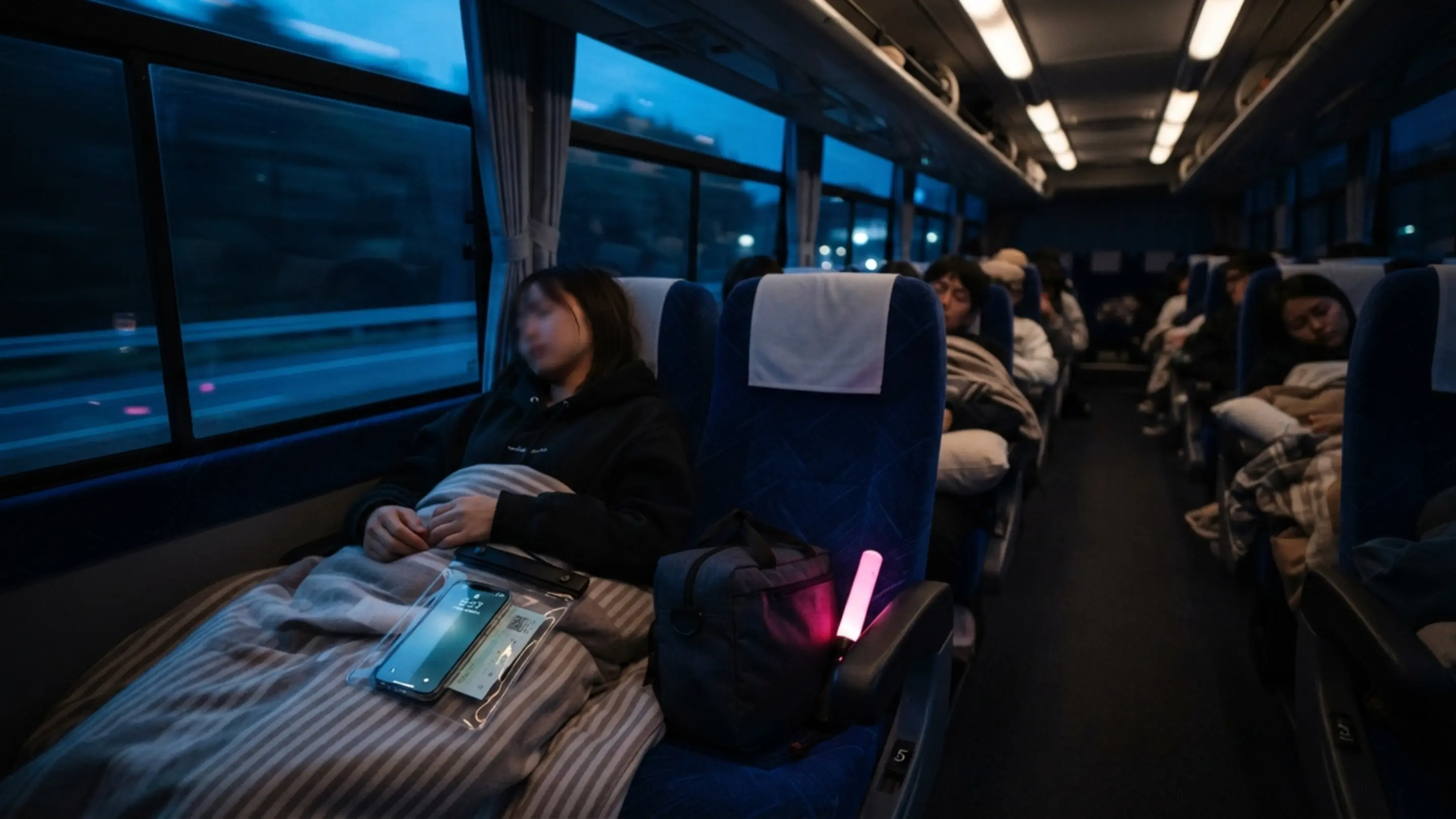 夜行バスに乗ってライブ遠征する様子。座席に荷物を置き、チケットとスマートフォンを手に待つ姿